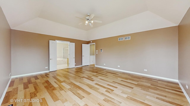 unfurnished bedroom with ceiling fan, ensuite bath, a tray ceiling, and light hardwood / wood-style floors