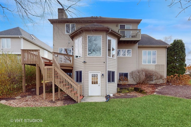 rear view of property with a wooden deck, a lawn, and a balcony