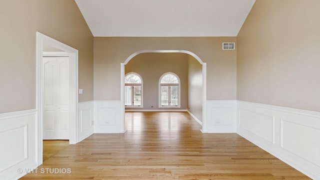 unfurnished room featuring lofted ceiling and light wood-type flooring