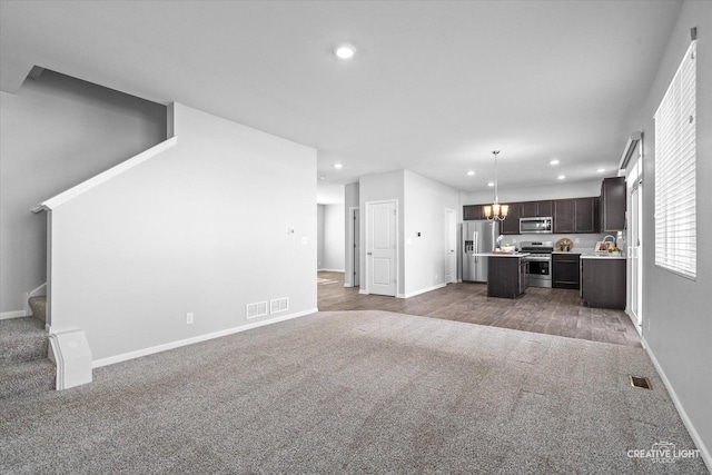 unfurnished living room with an inviting chandelier and carpet flooring