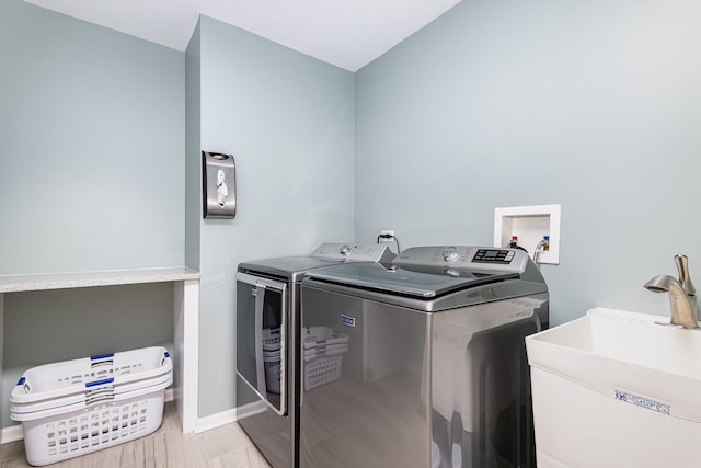 laundry area with separate washer and dryer and sink