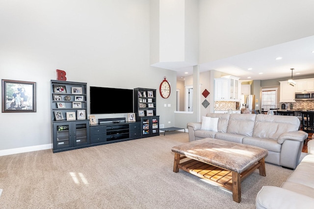 living room with a high ceiling and light carpet