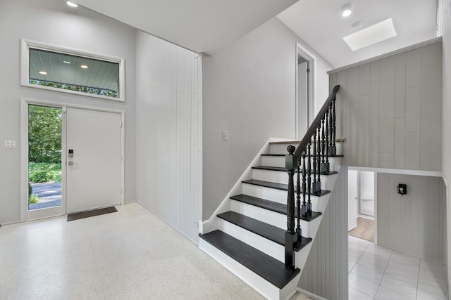 foyer featuring a skylight and wood walls