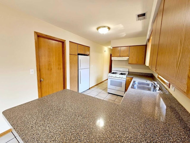 kitchen with sink, white appliances, light tile patterned floors, and kitchen peninsula