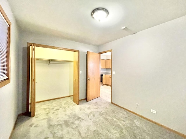 unfurnished bedroom featuring light carpet and a closet