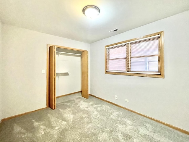 unfurnished bedroom with light colored carpet and a closet