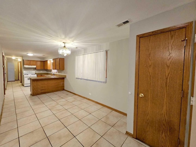 kitchen with light tile patterned flooring, an inviting chandelier, kitchen peninsula, and white gas range oven