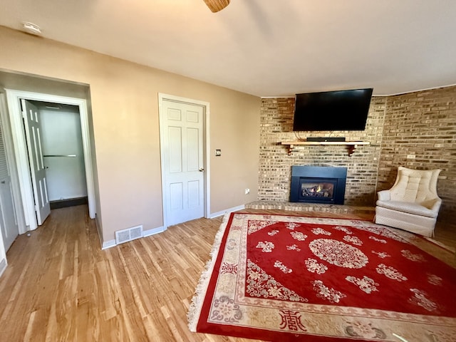 living room with a brick fireplace and wood-type flooring