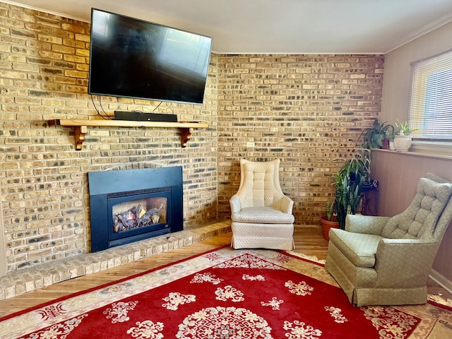 living room with crown molding, brick wall, and a brick fireplace