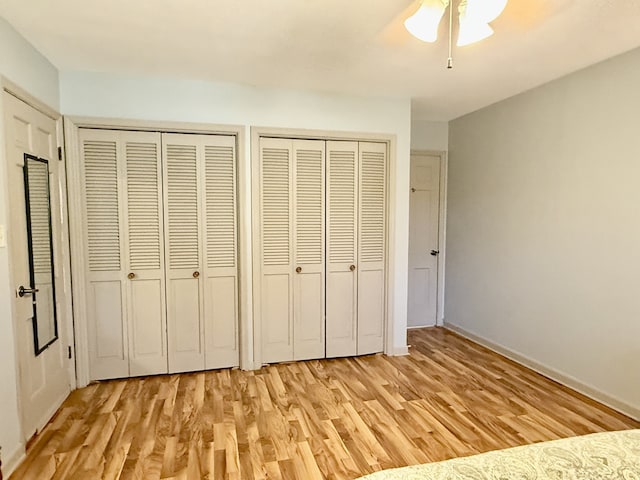 unfurnished bedroom featuring multiple closets, ceiling fan, and light hardwood / wood-style flooring