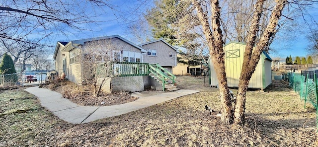 back of property featuring a deck and a shed