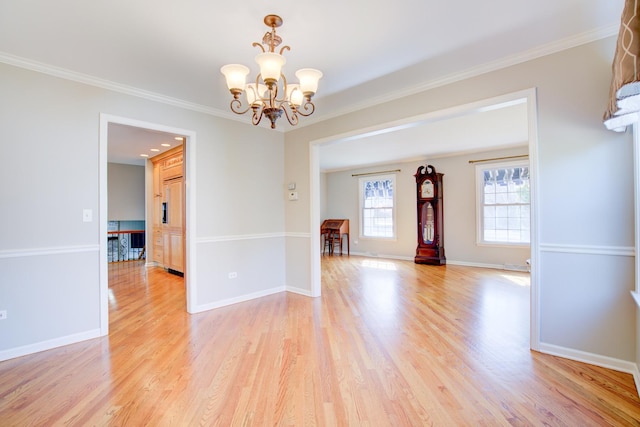 unfurnished room featuring crown molding, light wood-style flooring, baseboards, and a chandelier