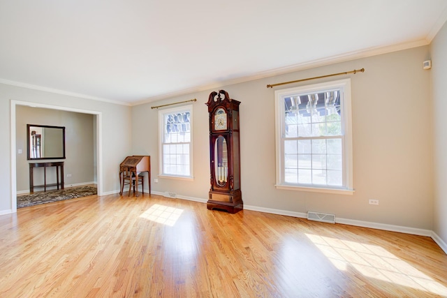 unfurnished room featuring ornamental molding, baseboards, visible vents, and light wood-type flooring