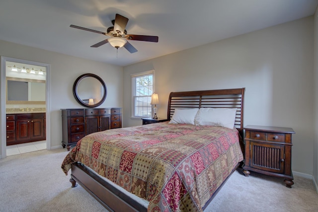 bedroom with ensuite bathroom, a ceiling fan, a sink, baseboards, and light colored carpet