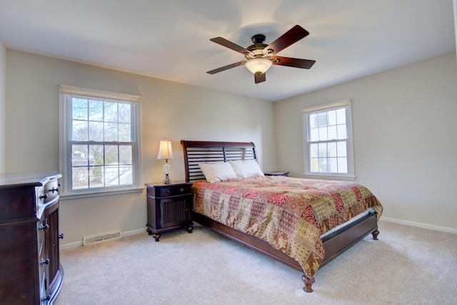 bedroom with visible vents, light carpet, multiple windows, and baseboards