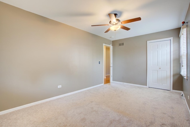 unfurnished bedroom featuring visible vents, baseboards, light colored carpet, a closet, and a ceiling fan