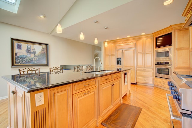 kitchen with lofted ceiling with skylight, built in appliances, a center island with sink, light wood-style floors, and a sink