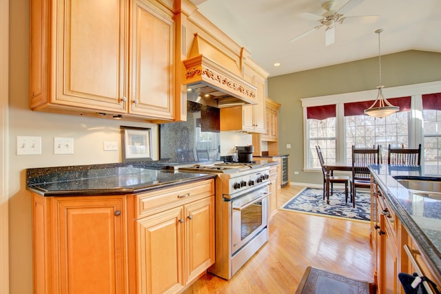 kitchen featuring decorative light fixtures, dark stone counters, light wood-type flooring, lofted ceiling, and high end stainless steel range