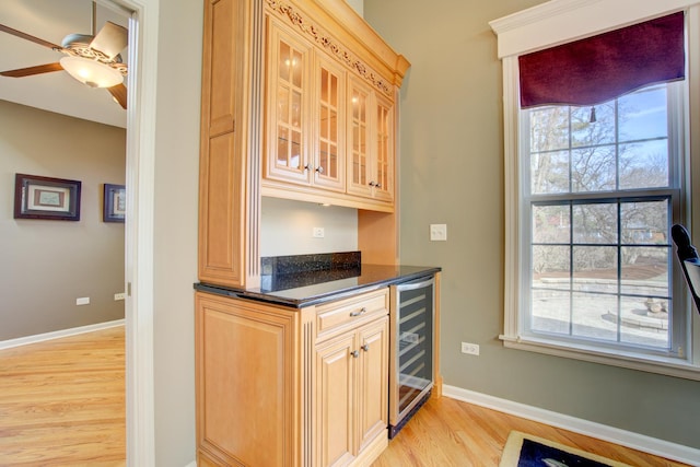 bar featuring ceiling fan, baseboards, wine cooler, and light wood-style flooring