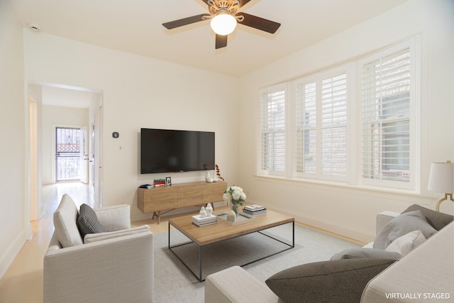 living area with baseboards and a ceiling fan