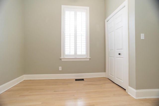 unfurnished bedroom with a closet, baseboards, light wood-style floors, and visible vents