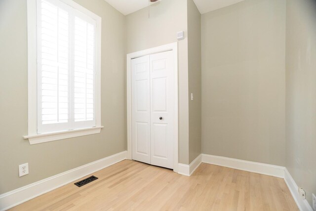 unfurnished bedroom with wood finished floors, visible vents, a closet, and baseboards