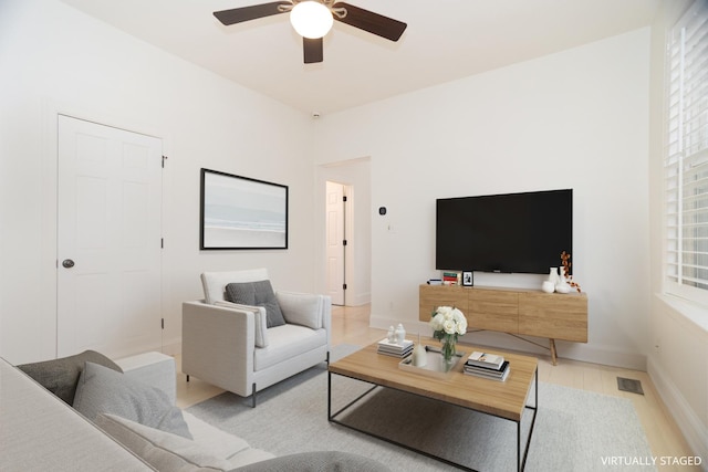 living area with visible vents, baseboards, and a ceiling fan