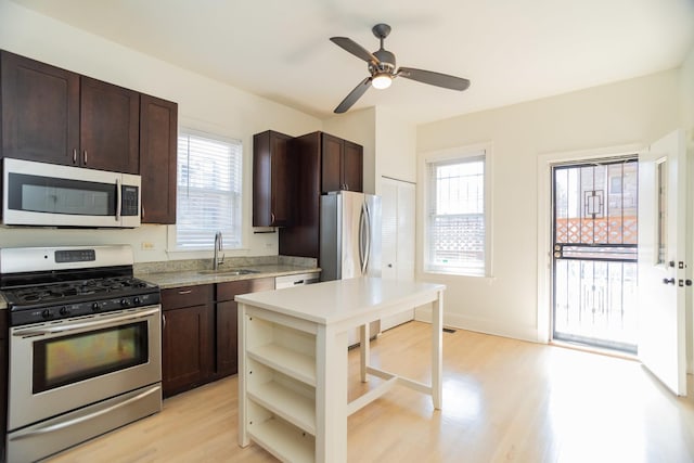 kitchen featuring a sink, dark brown cabinetry, light countertops, stainless steel appliances, and open shelves