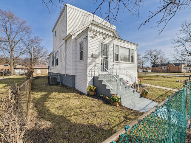 view of front of property featuring central air condition unit, fence private yard, and a front lawn