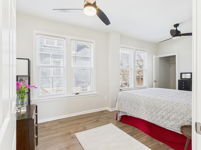 bedroom with a ceiling fan, wood finished floors, and baseboards