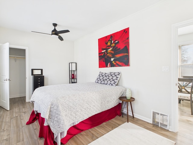 bedroom featuring ceiling fan, wood finished floors, visible vents, and baseboards