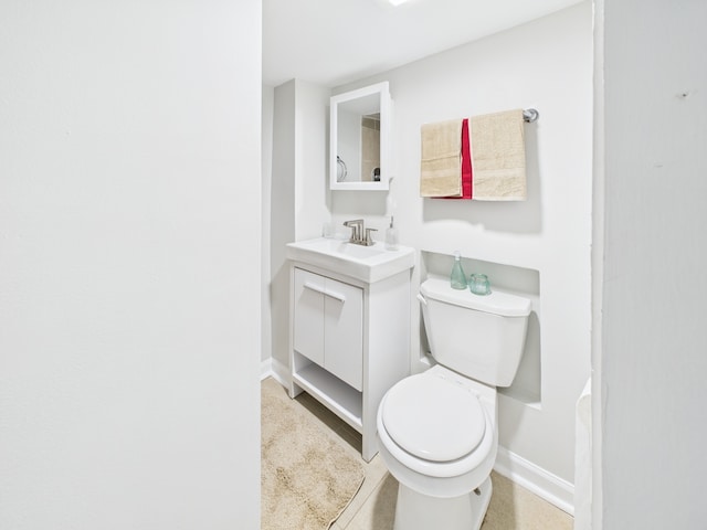 bathroom with toilet, vanity, and baseboards