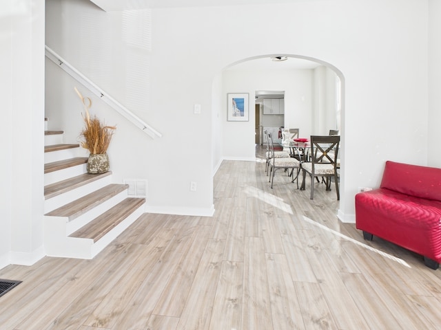 interior space featuring arched walkways, visible vents, baseboards, and wood finished floors