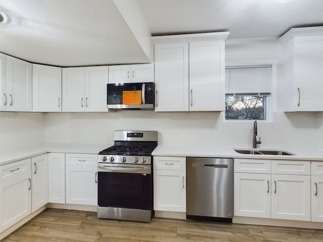 kitchen with stainless steel appliances, sink, and white cabinets