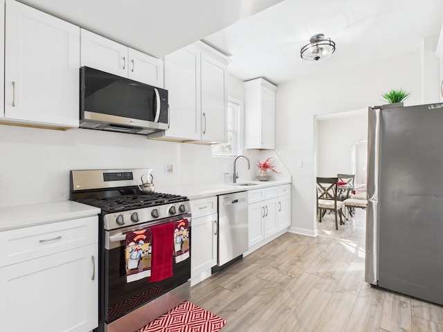 kitchen with white cabinetry, light countertops, appliances with stainless steel finishes, and a sink