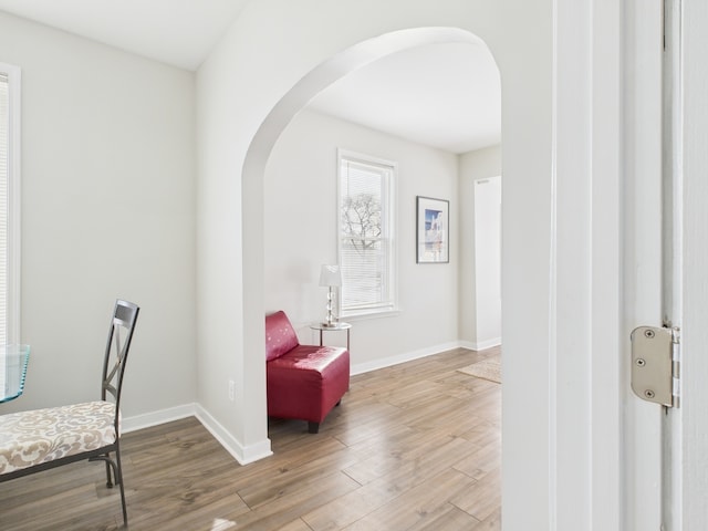 sitting room featuring baseboards, arched walkways, and wood finished floors