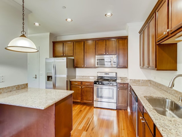 kitchen featuring sink, crown molding, light stone counters, pendant lighting, and stainless steel appliances