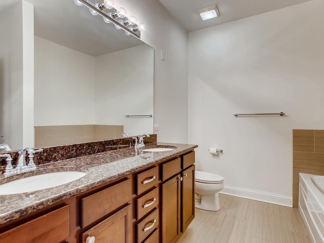 bathroom featuring vanity, a tub to relax in, and toilet