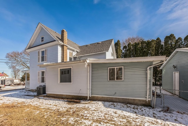 snow covered house featuring central AC unit