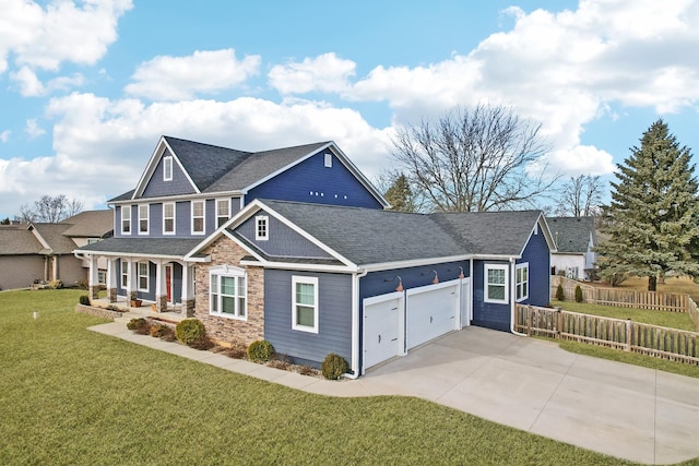 view of front of home with concrete driveway, stone siding, an attached garage, fence, and a front yard