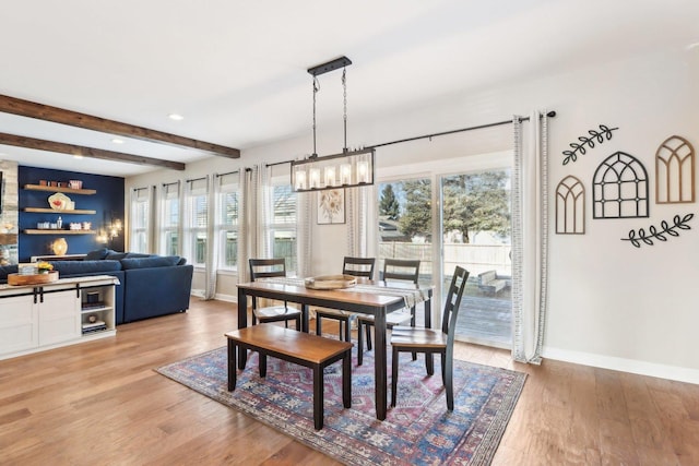 dining space featuring an inviting chandelier, beamed ceiling, and light wood-type flooring