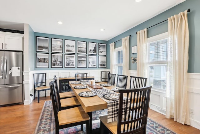 dining space with light wood-type flooring, a wainscoted wall, a decorative wall, and recessed lighting