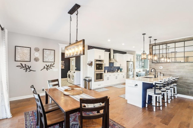 dining room featuring recessed lighting, baseboards, wood finished floors, and independent washer and dryer