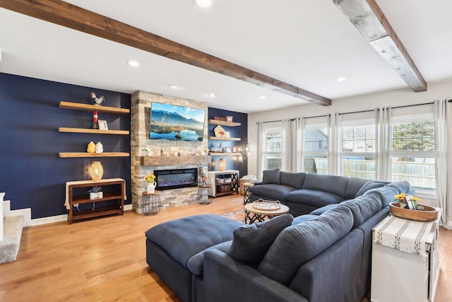 living room with light wood finished floors, recessed lighting, beam ceiling, and a stone fireplace