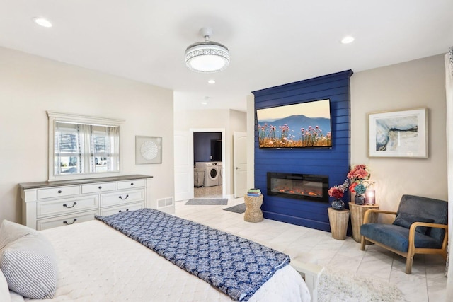 bedroom with a large fireplace and washing machine and dryer