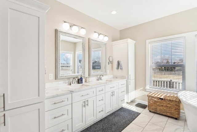 full bathroom featuring double vanity, a freestanding bath, baseboards, and a sink