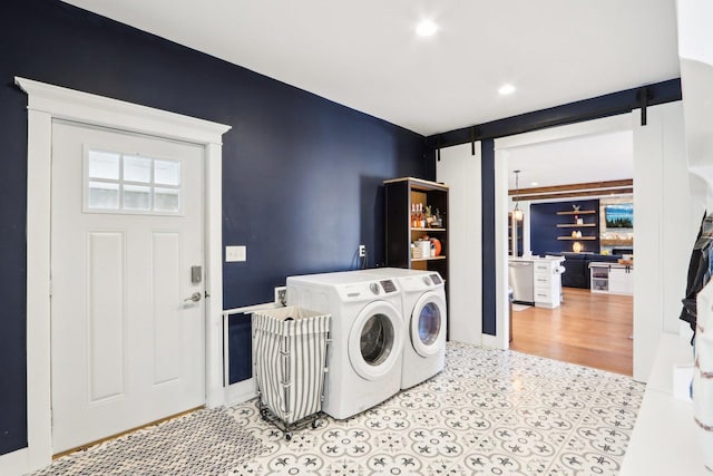 laundry room featuring a barn door, separate washer and dryer, and light tile patterned floors