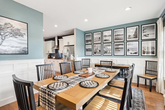 dining room with recessed lighting, a wainscoted wall, a decorative wall, and light wood finished floors