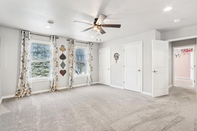 empty room with ceiling fan and light carpet