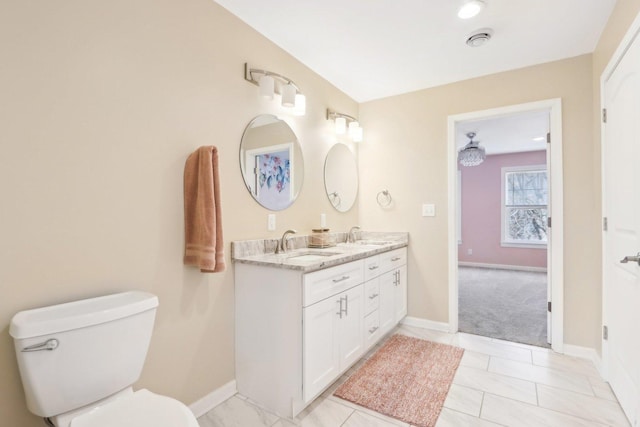 full bathroom featuring toilet, double vanity, baseboards, and a sink